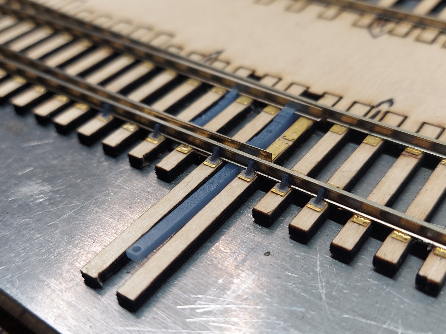 Side view of Roadmaster Series HO turnout rail braces installed on prototype-style tie plates.